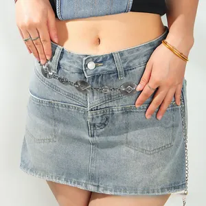 Detail of vintage silver metal waist chain with engraved geometric patterns on denim skirt