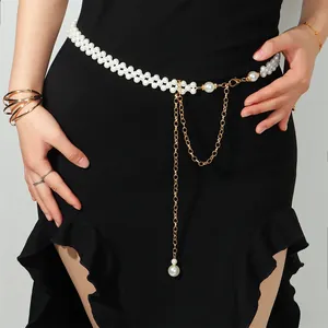 Detail einer Perlen-Taillenkette mit goldenen Quasten auf schwarzem Kleid
