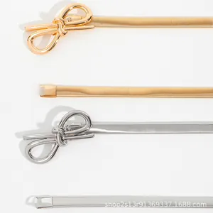 Detail of elegant gold and silver elastic snake chain belts with bow-shaped metal buckles