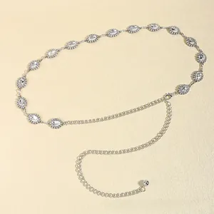 Detail of silver chain belt with oval crystals and rhinestone settings on beige background