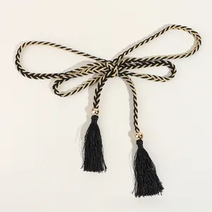 Detail of woven rope belt with black tassels and decorative golden metal beads