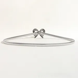 Macro detail of silver metal elastic belt featuring a decorative 3D bow buckle