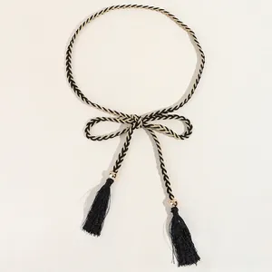 Détail de la chaîne de taille tissée noir et or avec glands en soie et billes dorées