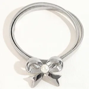 Detail of silver stretch metal belt featuring a bow buckle with a central faux pearl