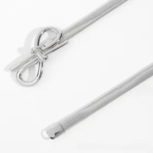 Detail of silver elastic snake chain belt with a polished metallic bow buckle