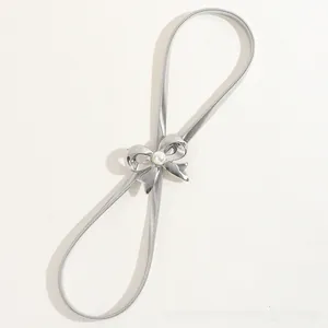 Detail of silver elastic metal belt featuring hollow bow buckle and white faux pearl accent