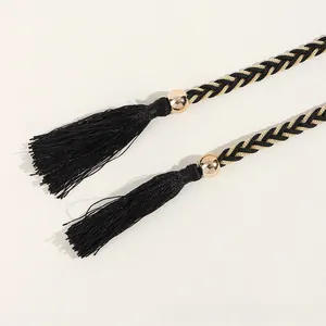 Détail de ceinture tressée noir et or avec pompons élégants et perles dorées