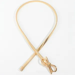 Detail of elegant gold metal waist chain with a minimalist bow buckle design