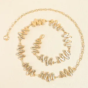 Détail d'une ceinture chaîne en métal doré élégante avec des maillons en forme de M