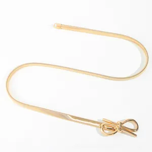 Detail of gold bow buckle on elastic metal snake chain belt for elegant dress
