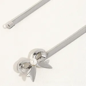 Close-up of silver metal elastic belt featuring a bow buckle with a faux pearl inlay