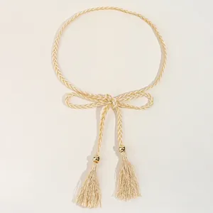 Détail d'une ceinture tressée avec franges, nœud élégant et perles dorées