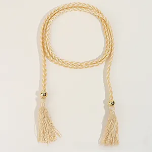 Détail d'une ceinture tressée beige avec perles dorées et glands pour robe