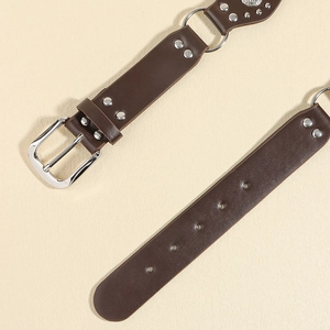 Détail d'une ceinture en similicuir marron foncé avec rivets et boucle métallique style western