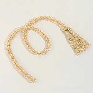 Détail de la ceinture tressée dorée avec perles métalliques et élégants glands soyeux