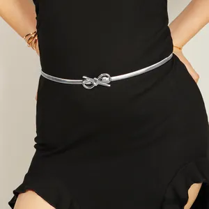 Close-up of a slim silver metal chain belt with a bow buckle on a black dress