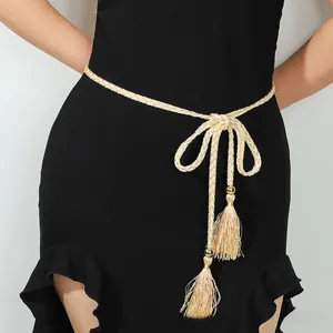 Détail de ceinture tressée or champagne avec pompons sur une robe noire ajustée