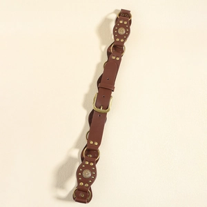 Détail d'une ceinture marron en cuir PU style Y2K avec anneaux en laiton et rivets fleuris