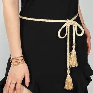 Détail de la ceinture tressée beige avec perles dorées et longs glands en soie sur robe