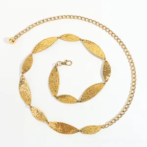 Detailed macro view of gold leaf-shaped metal waist chain with hammered texture finish