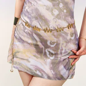 Détail d'une élégante chaîne de taille dorée en métal portée sur une robe à fleurs