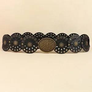 Dettaglio della cintura bohémien in pelle nera con dischi solari in metallo bronzato