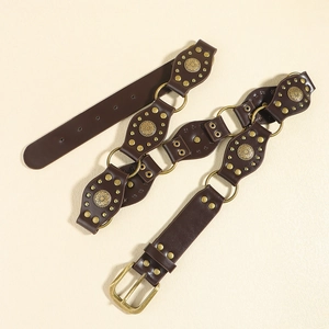 Détail d'une ceinture en cuir marron bohème avec boucles florales en bronze et anneaux
