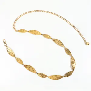Detail of golden leaf-shaped metal chain belt featuring hammered texture and lobster clasp