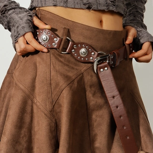 Détail d'une ceinture en cuir PU marron avec rivets et anneaux sur une jupe en daim