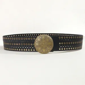 Détail d'une ceinture en cuir noir avec œillets et boucle mandala soleil sculptée