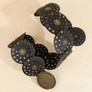 Dettaglio cintura boho in pelle nera con borchie a stella e fibbia in metallo vintage incisa