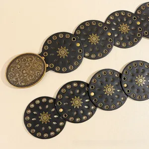 Dettaglio cintura bohémien in pelle con borchie a sole e fibbia vintage in bronzo sbalzato