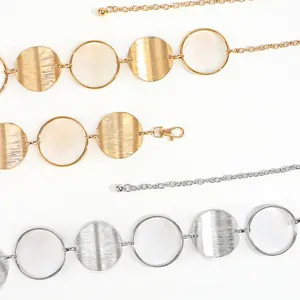 Detail view of the metal waist chain showing hollow rings and brushed texture discs in gold and silver