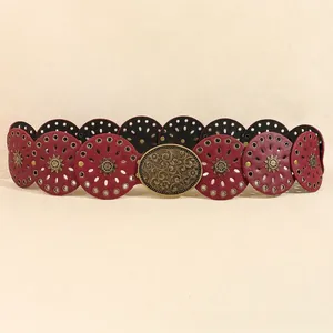 Dettaglio di cintura in pelle boho con borchie floreali in bronzo e fibbia vintage