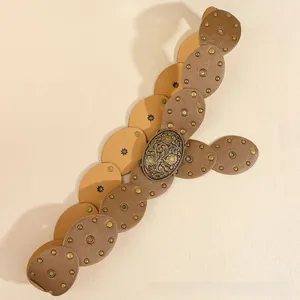 Gros plan sur une ceinture Y2K en similicuir avec rivets en bronze et boucle florale gravée