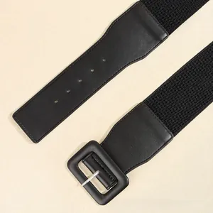 Detail view of a black wide elastic belt featuring a large leather-wrapped square buckle