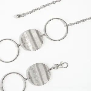 Macro detail of silver metal waist chain featuring hollow rings and brushed texture discs