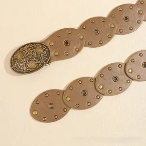 Détail de la ceinture bohème en cuir marron avec boucle florale et rivets en métal