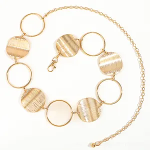 Detail of vintage gold metal waist chain with hollow rings and brushed textured discs