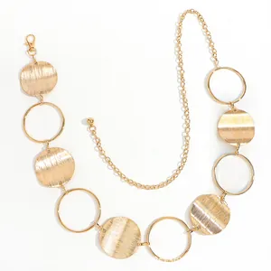 Detail of gold metal waist chain with brushed textured discs and adjustable ball end link