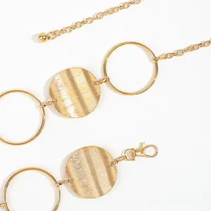 Detail of vintage gold metal chain belt featuring hollow circular plates and lobster clasp