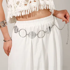 Detail view of ethnic hollow metal waist chain with brushed texture on a white dress