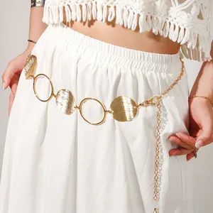Close-up of vintage golden waist chain with hollow round discs on a white dress