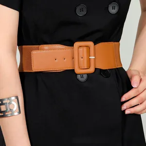 Detail of brown wide elastic waist belt with large square buckle on a model's waist