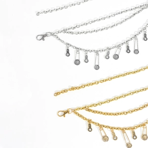 Detailed view of multilayer chain belts with lion head charms and pin pendants in gold and silver