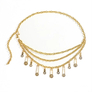 Detailed close-up of multilayered gold metal waist chain with vintage coin and safety pin