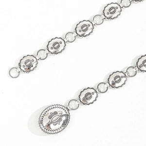 Détail macro d'une ceinture concho bohème argentée avec gravures de fleurs solaires