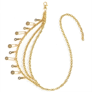 Detail of layered gold metal waist chain with vintage coins and safety pin charms