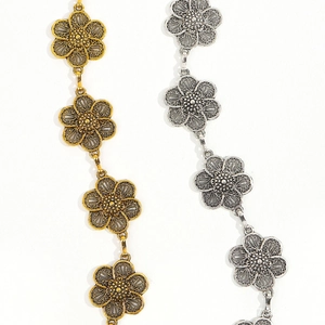 Detail view of retro flower metal waist chains in gold and silver with hollow petals