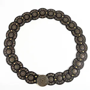 Detail van bohemien riem met bronzen mandala-gesp en zwarte schijven met oogjes
